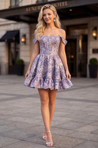 A model poses in a stylish lilac mini dress with off-the-shoulder sleeves and a ruffled hem, standing outside an elegant hotel.