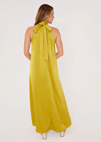A model showcases a stunning golden olive satin gown with a high neckline and a stylish bow-tie detail at the back. Perfect for elegant events like galas or weddings, this gown is conveniently available near Apex, Cary, and Raleigh.