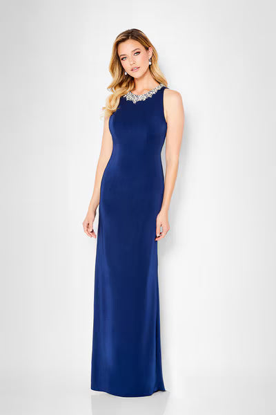 A model showcases an elegant navy A-line gown with a jeweled neckline, perfect for formal events such as mother of the bride or black tie weddings. This stylish dress is conveniently located near Apex, Cary, and Raleigh for easy access.