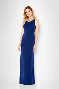 A model showcases an elegant navy A-line gown with a jeweled neckline, perfect for formal events such as mother of the bride or black tie weddings. This stylish dress is conveniently located near Apex, Cary, and Raleigh for easy access.