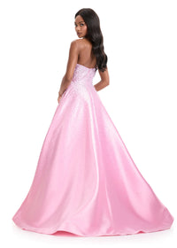 A model showcases a stunning strapless A-line gown in a soft ice pink hue, adorned with sparkling crystal and pearl details.