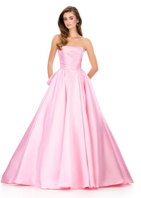 A model showcases a stunning strapless ice pink gown with a fitted bodice and flowing skirt, perfect for elegant occasions such as prom, homecoming, or black tie weddings. This dress is conveniently located near Apex, Cary, and Raleigh.