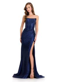 A model confidently showcases a stunning navy strapless gown adorned with sparkling embellishments and a thigh-high slit.