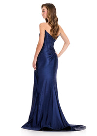 A woman models a stunning navy strapless gown with a fitted silhouette and sparkling embellishments, showcasing a dramatic train.