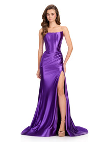 A stunning model showcases a sleek, strapless purple gown featuring a structured corset bodice and a thigh-high slit. This elegant dress is perfect for special occasions like prom or galas, conveniently located near Apex, Cary, and Raleigh.