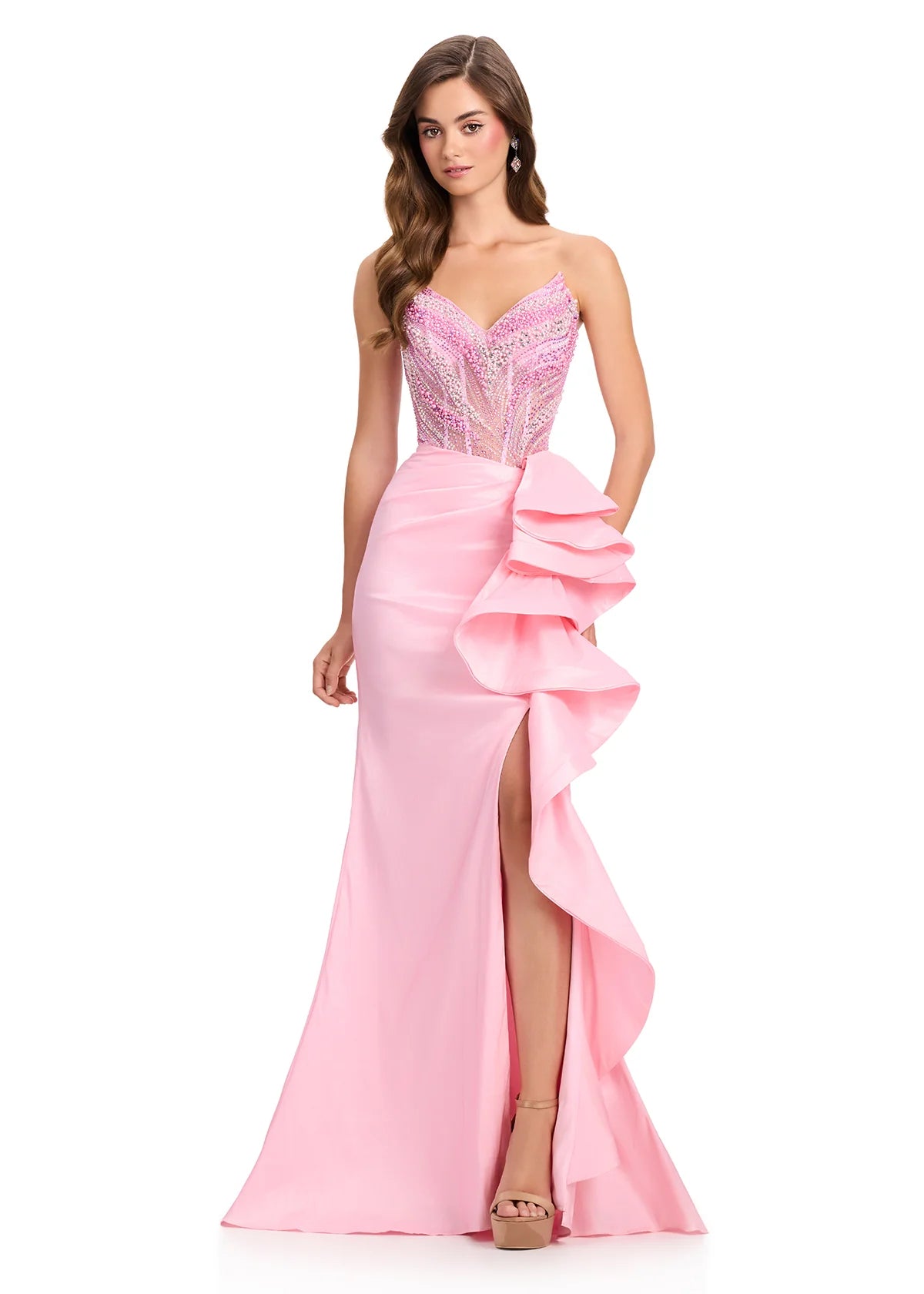 A model showcases an elegant ice pink gown featuring a beautifully embellished bodice and a sleek silhouette with a dramatic ruffle detail along the side.