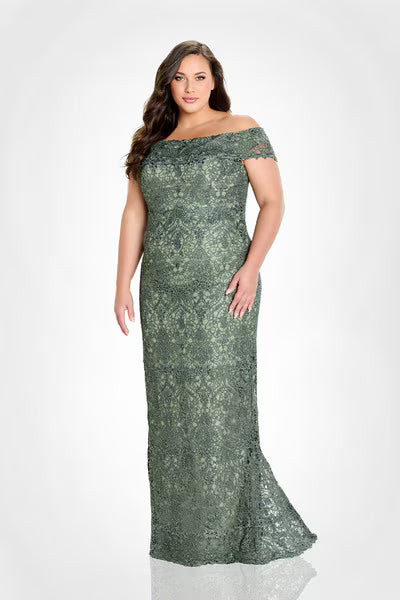 A plus-size model showcases an elegant off-the-shoulder allover lace sheath gown in a rich olive hue. This stunning dress is perfect for special occasions like mother of the bride events or formal galas, available near Apex, Cary,.