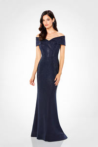 A model showcases a stunning navy off-the-shoulder gown, featuring a fitted silhouette adorned with shimmering details.