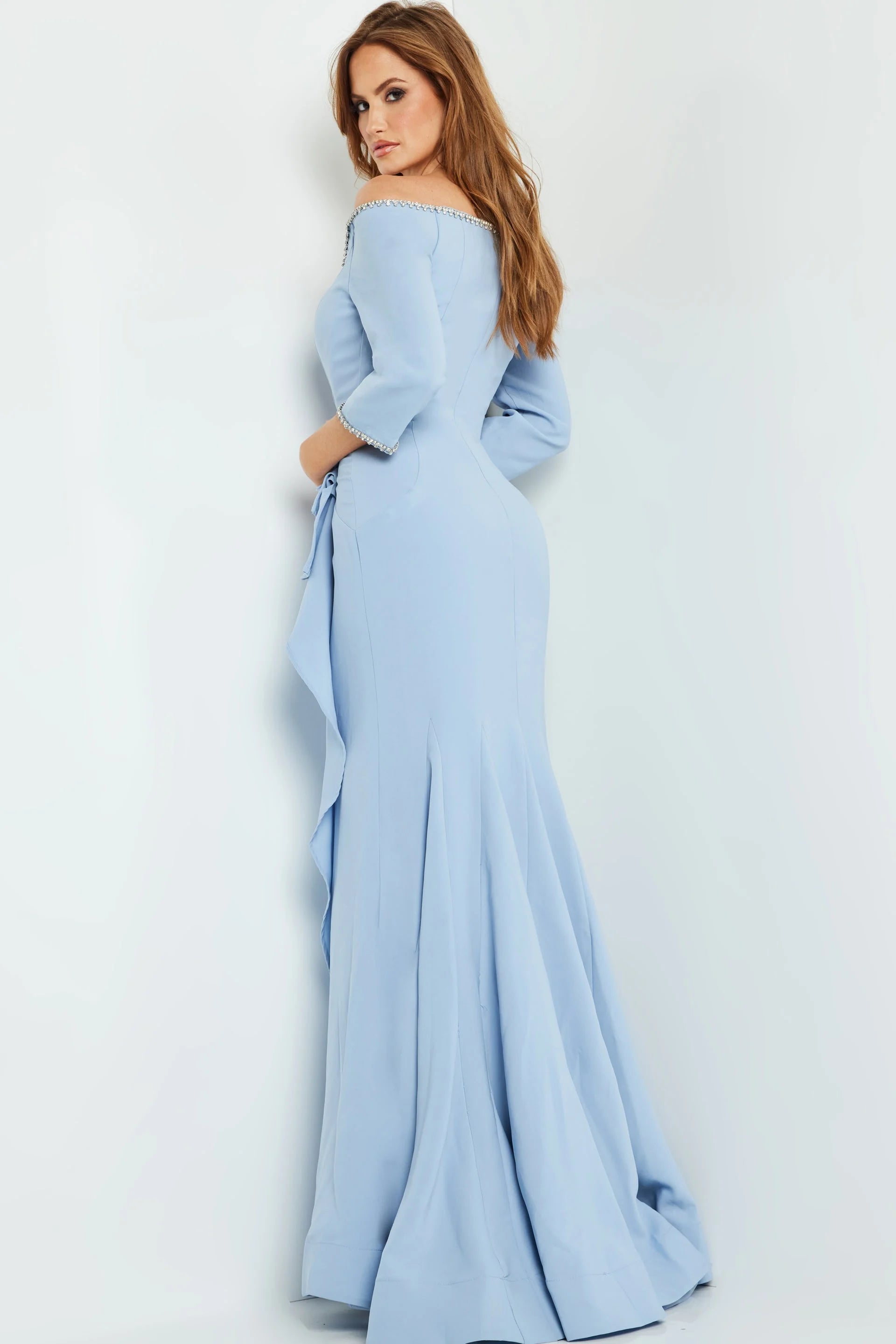 A model wears a stunning light blue off-the-shoulder mermaid gown featuring elegant detail along the neckline and a flowing train.