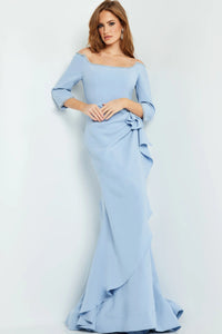 A model poses in an elegant light blue mermaid gown with off-the-shoulder sleeves and ruffled detailing.