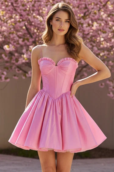 A model showcases a flirty pink mini dress with a ruched bustier bodice and a full skirt, perfect for birthday parties or date nights. The dress is set against a backdrop of blooming pink flowers, adding to its feminine charm.