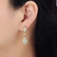 A close-up of a womans ear adorned with elegant geometric drop stud earrings featuring sparkling cubic zirconia set in a gold-filled design. These earrings are perfect for special occasions like weddings or galas, adding a touch of glamour.
