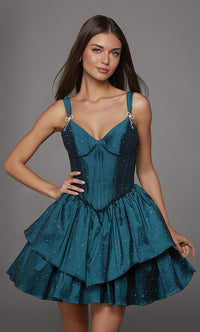 A model poses in a stunning teal dress featuring a fitted bodice with decorative straps and a flared, layered skirt adorned with sparkles.