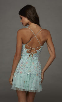 A model showcases a stunning light blue mini dress with intricate beadwork and a layered tulle skirt, featuring a crisscross back design.