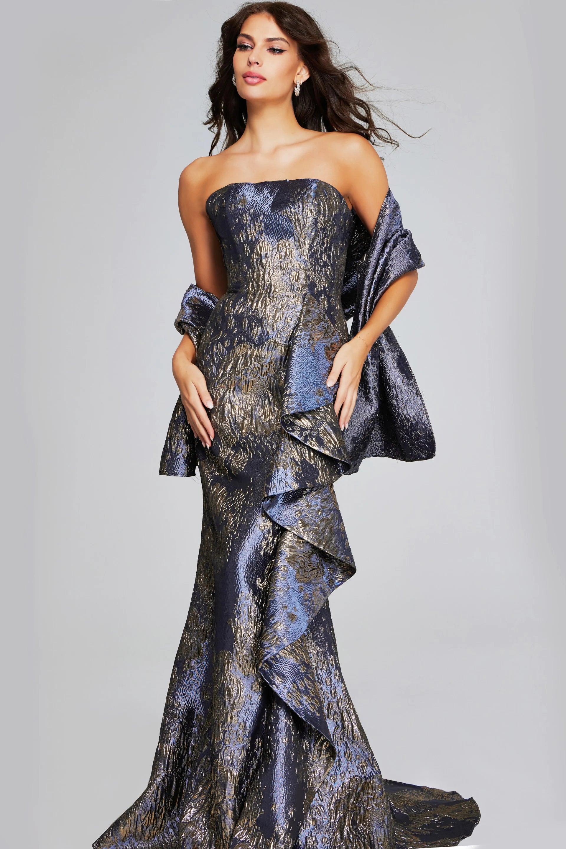 A model showcases a stunning strapless mermaid gown with side ruffles in a shimmering gunmetal and gold fabric.