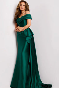 A model poses in a stunning emerald green floor-length gown with an off-the-shoulder sweetheart neckline and soft pleats cascading down one side.