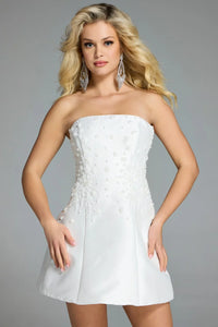 A model poses in a strapless off-white dress adorned with intricate floral embellishments, showcasing a fitted bodice and a flared skirt.