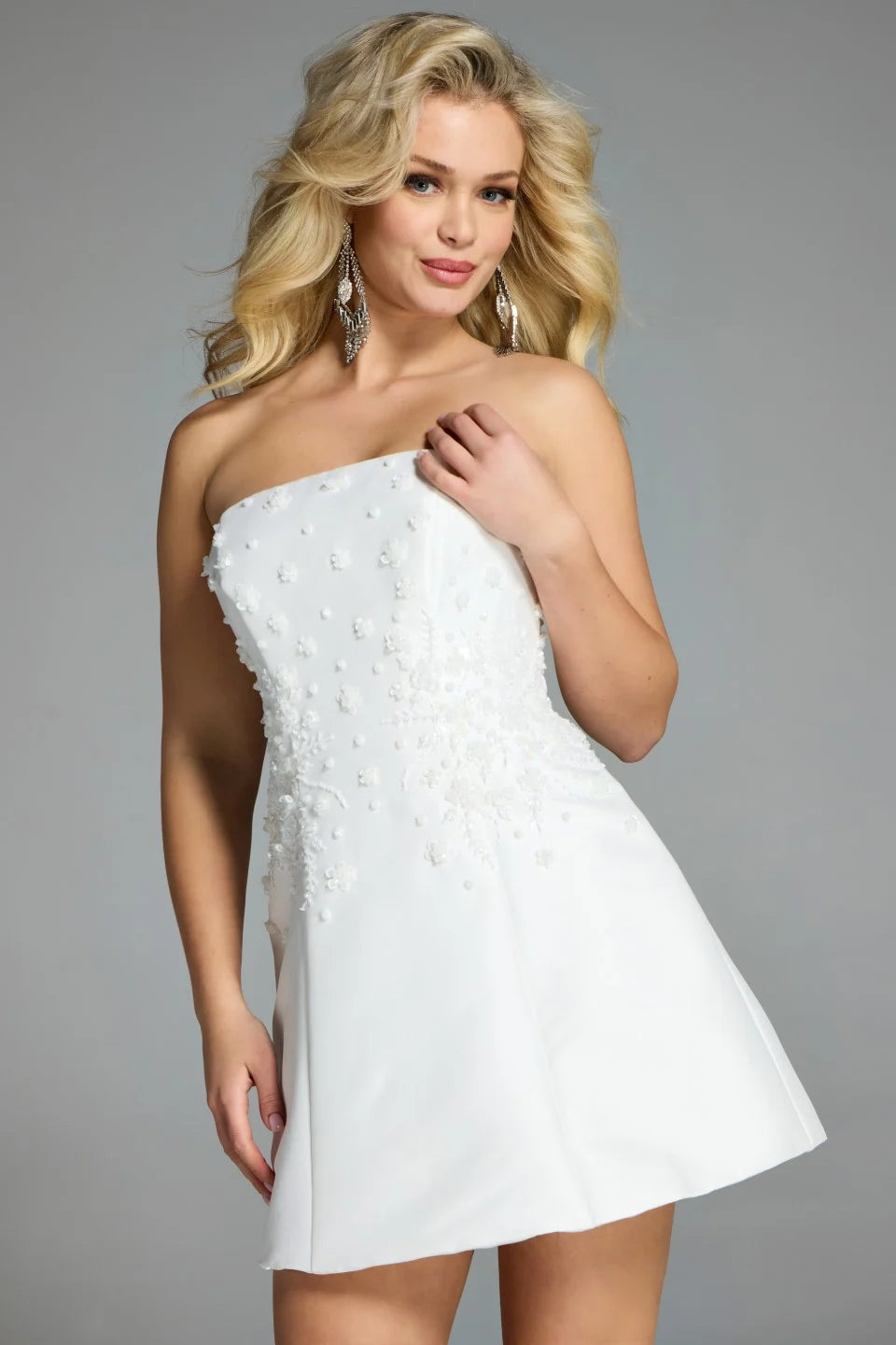 A model poses in a stunning off-white strapless dress adorned with delicate floral embellishments. This chic mini dress is perfect for events like prom, date nights, or birthday parties, and is conveniently located near Apex, Cary,.
