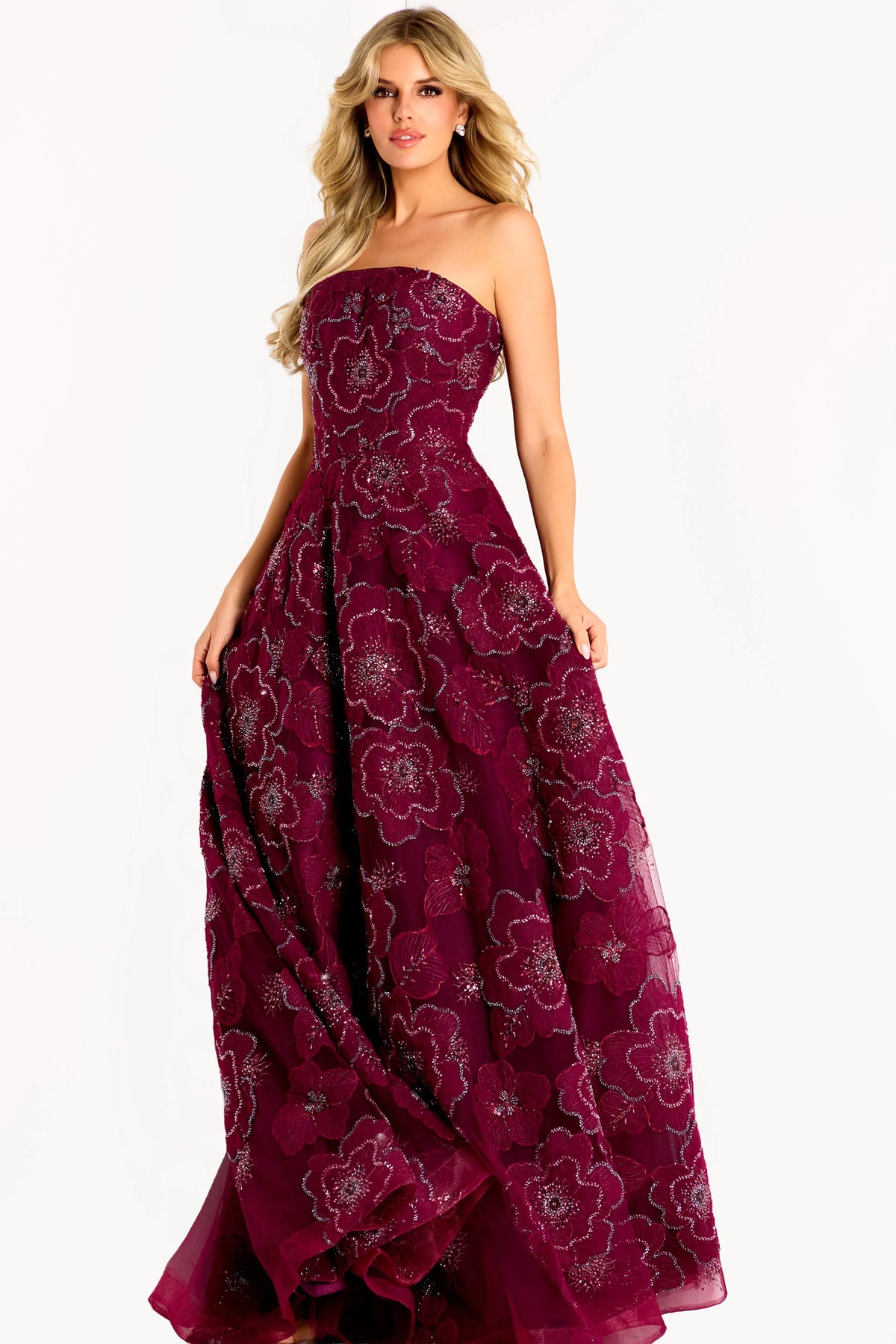 A model showcases a stunning burgundy strapless A-line gown adorned with floral appliqué and sparkling details.