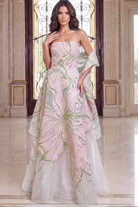 A model showcases an elegant strapless gown featuring intricate pink floral embroidery and a flowing sheer overlay, perfect for formal occasions like a gala or black tie wedding.