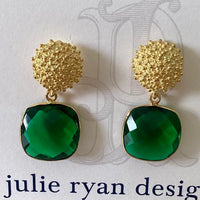 A pair of elegant earrings featuring a textured gold stud and a large, faceted green gemstone drop. These stunning earrings are perfect for formal occasions like galas or black tie weddings, adding a touch of sophistication to any outfit.