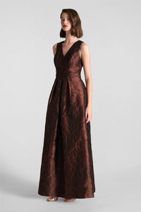 A model showcases the elegant Mariah Gown in chocolate, featuring a deep V-neck and a flowing silhouette.