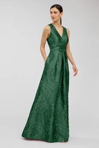 A model showcases the elegant Mariah Gown in emerald green, featuring a V-neck design and a textured jacquard fabric.