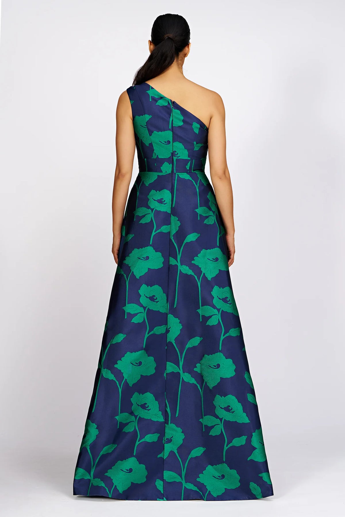 Elegant one-shoulder gown featuring a striking navy base adorned with vibrant green floral patterns. This stunning piece is perfect for formal events like galas or black-tie weddings and is conveniently located near Apex, Cary, and Raleigh.