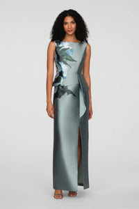 A model showcases an elegant floor-length gown with a sleek column silhouette, featuring a floral print and an asymmetrical peplum.