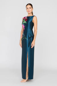 A model showcases the elegant Luciana Column Gown in a rich blue hue, featuring a stunning heirloom rose print and a sleek silhouette with a front slit.