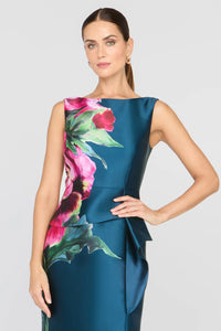A model showcases the Luciana Column Gown in Blue Opal, featuring a striking heirloom rose print and an elegant asymmetrical peplum.