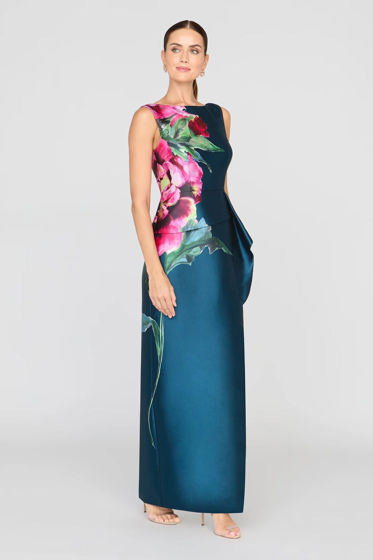 A model showcases the elegant Luciana Column Gown in Blue Opal, featuring a vibrant floral print and a sleek silhouette.