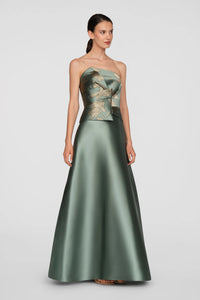 A model showcases a stunning sage green ball gown with metallic jacquard detailing and gold floral accents.