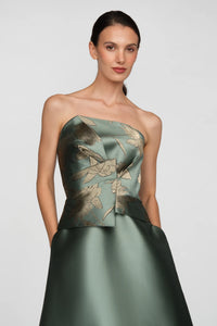 A model showcases a strapless sage ball gown featuring metallic jacquard folds and gold floral details.