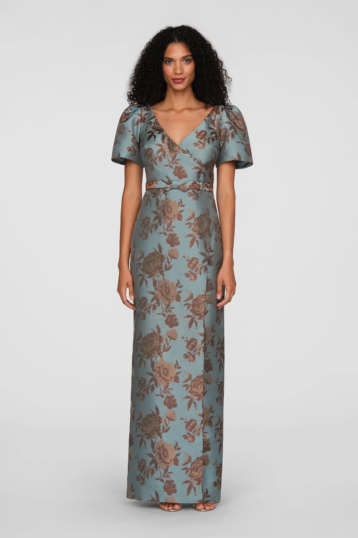 A model showcases a vintage floral jacquard gown in cool blue, featuring a faux-surplice bodice and short puff sleeves.
