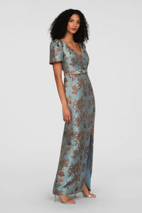 A model showcases a vintage floral jacquard gown in cool blue hues, featuring a faux-surplice bodice and short sleeves.
