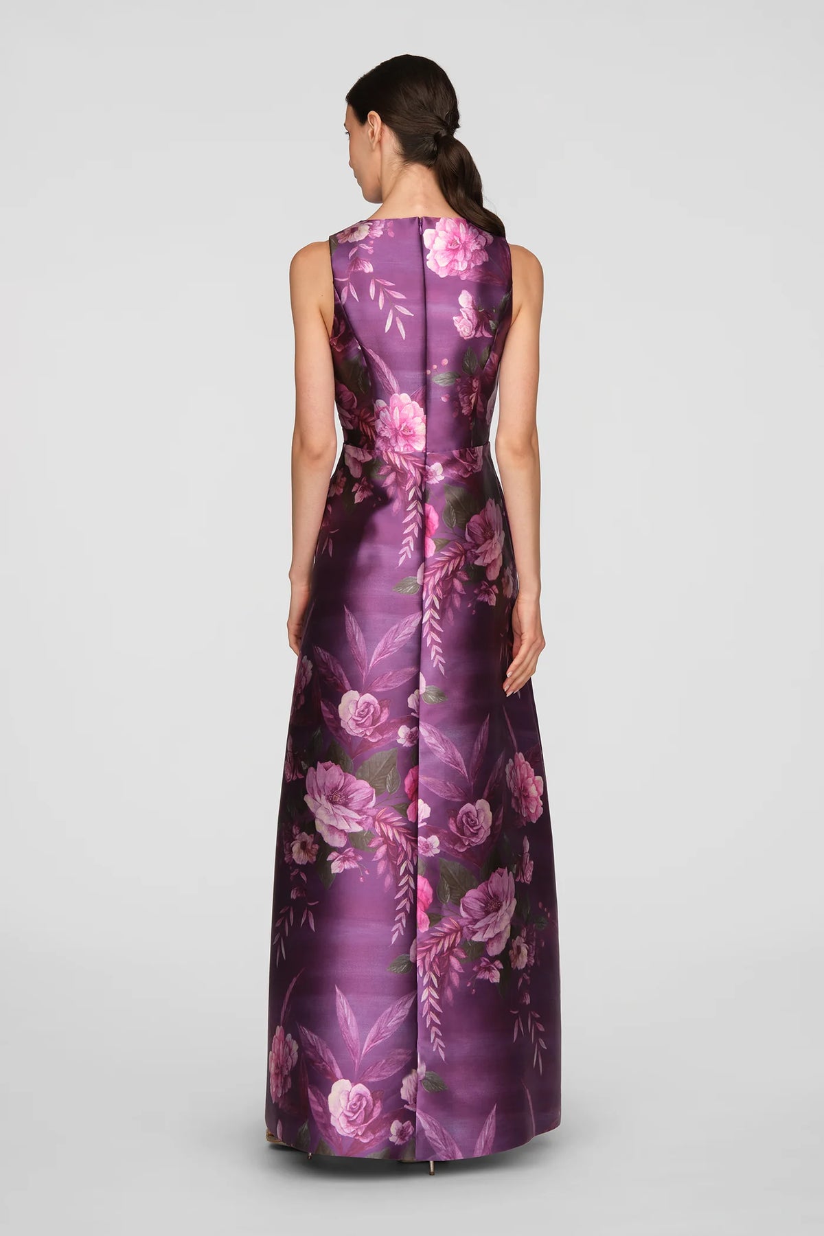 A model showcases a floor-length gown in vivid berry, adorned with a vibrant rose bouquet print. This elegant dress is perfect for formal occasions such as mother of the bride events, galas, or black tie weddings, and is conveniently.