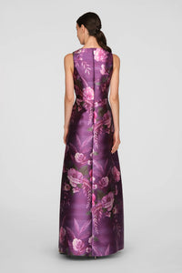 A model showcases a floor-length gown in vivid berry, adorned with a vibrant rose bouquet print. This elegant dress is perfect for formal occasions such as mother of the bride events, galas, or black tie weddings, and is conveniently.