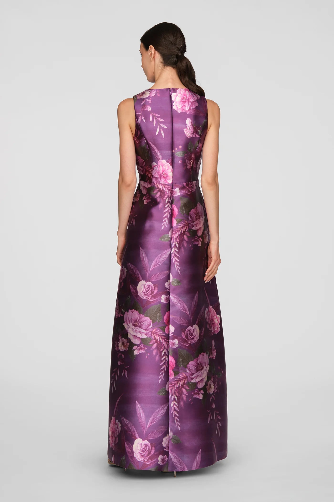 A model showcases a floor-length gown in vivid berry, adorned with a vibrant rose bouquet print. This elegant dress is perfect for formal occasions such as mother of the bride events, galas, or black tie weddings, and is conveniently.