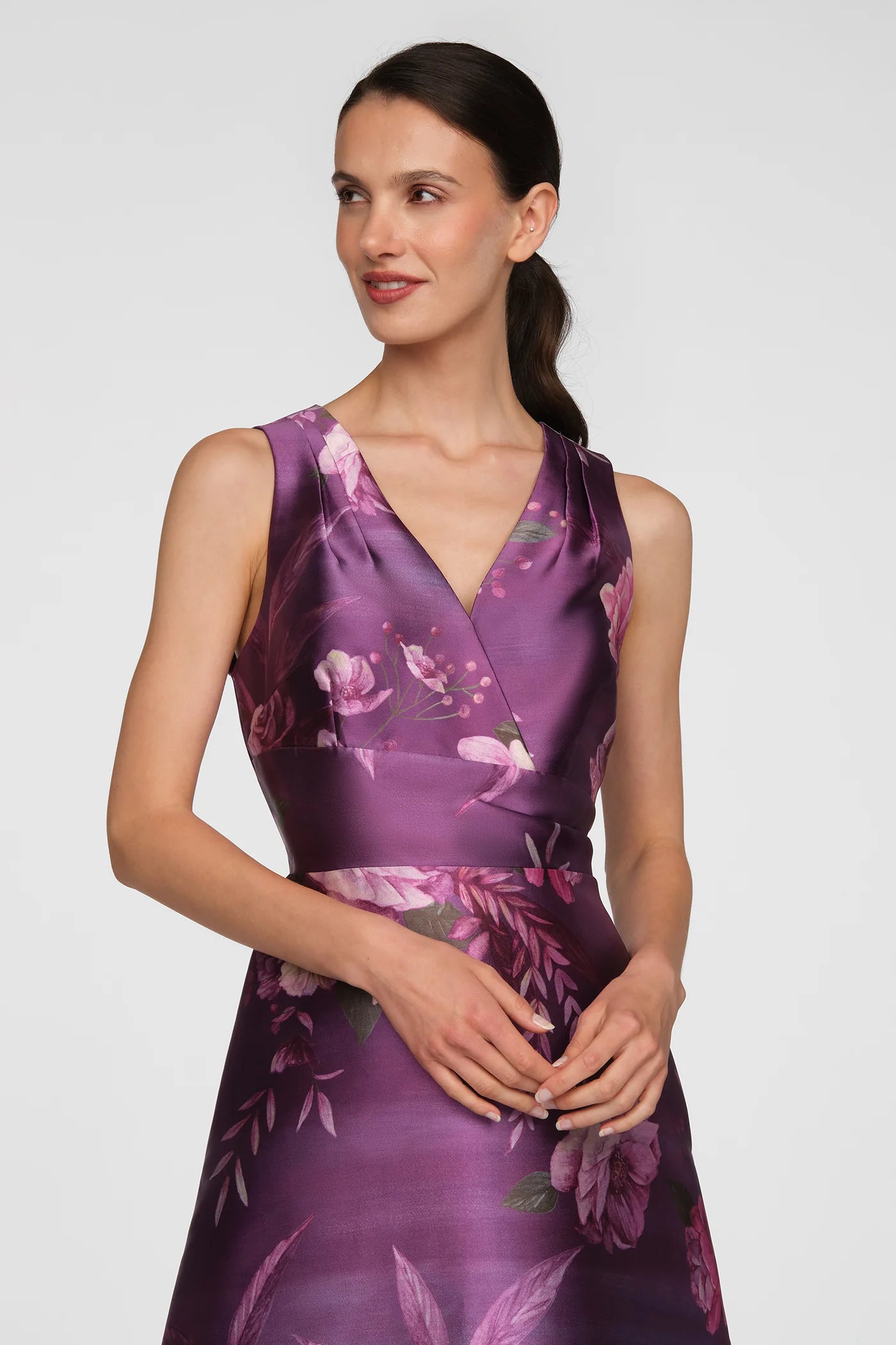 A model showcases a stunning floor-length gown in vivid berry, featuring a floral print with shades of purple and pink.