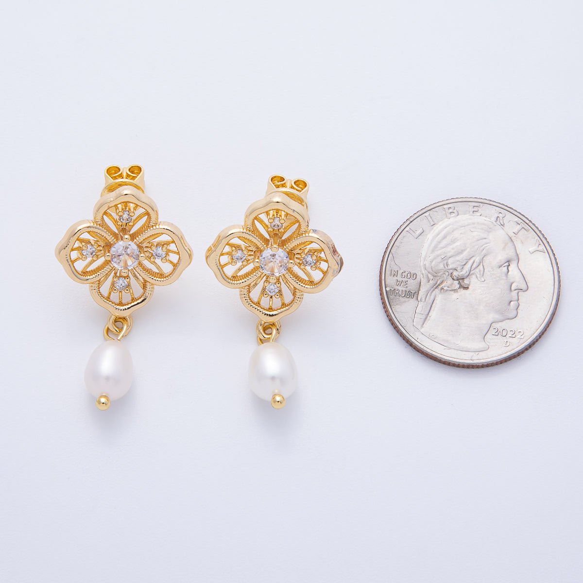 Gold flower filigree drop earrings feature intricate designs and a pearl accent, displayed next to a quarter for size reference.