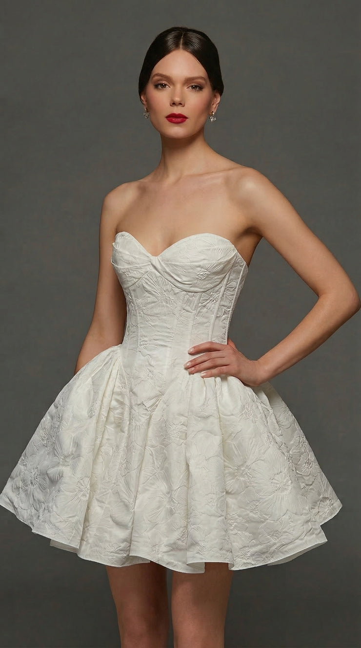 A model showcases a stunning white strapless dress with a fitted bodice and a flared skirt, featuring textured fabric.