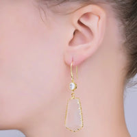 A close-up of a models ear showcasing elegant clear stone statement earrings. The earrings feature a gold-filled design with a cubic zirconia accent, perfect for adding a touch of glam to formal events like galas or weddings.