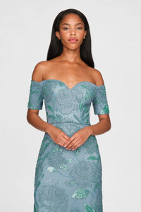 A model poses in a stunning teal blue off-shoulder gown adorned with intricate beading and floral designs. This elegant dress is perfect for special occasions like proms, galas, or black tie weddings, convenient to Apex, Cary, and Raleigh.