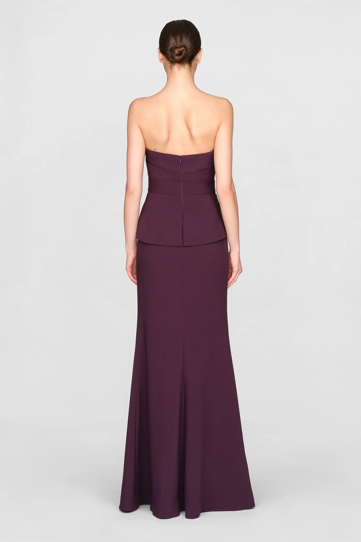 A model showcases a sleek, strapless purple gown with a fitted bodice and a flowing floor-length skirt, perfect for events like galas or black tie weddings. This elegant dress is conveniently located near Apex, Cary, and Raleigh.
