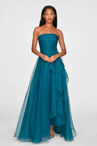 A model showcases a stunning strapless draped gown in a rich teal color, featuring a flowing skirt with layered ruffles.
