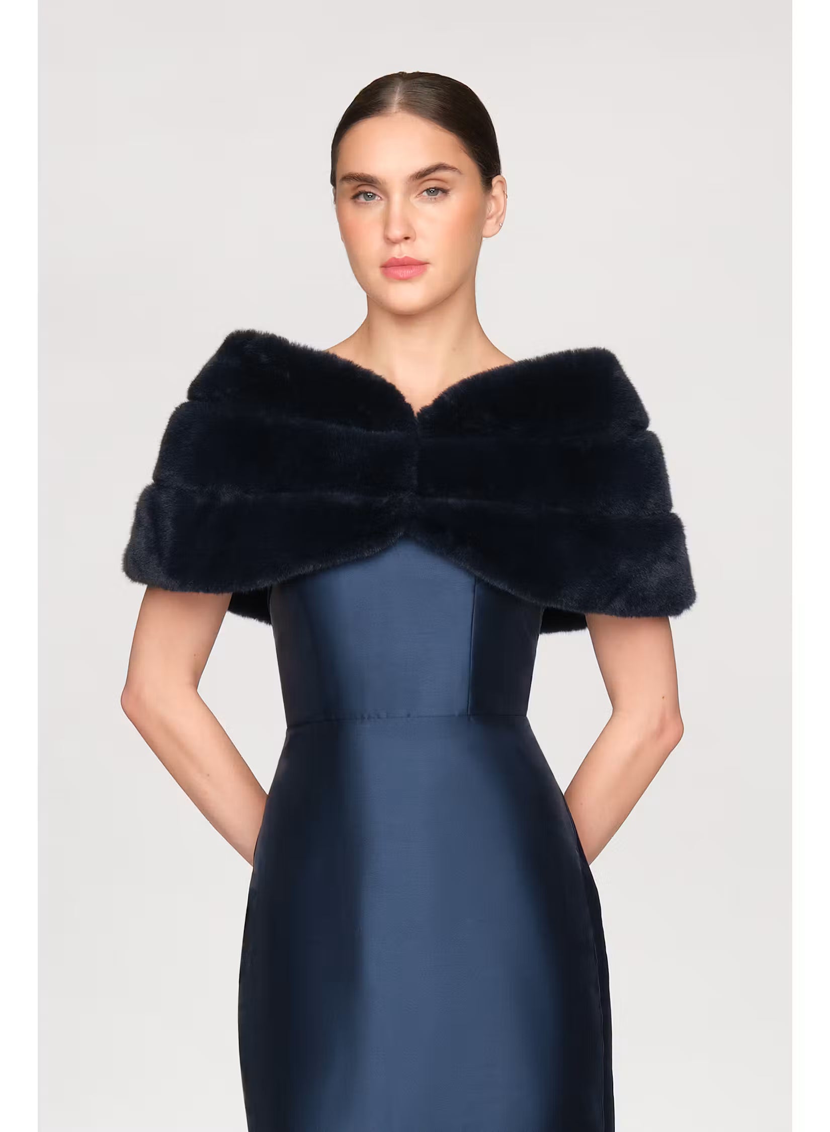 A model showcases a luxurious navy faux mink shawl draped elegantly over a sleek, fitted gown. This stylish accessory is perfect for formal occasions like black tie weddings or galas, and is conveniently available near Apex, Cary,.