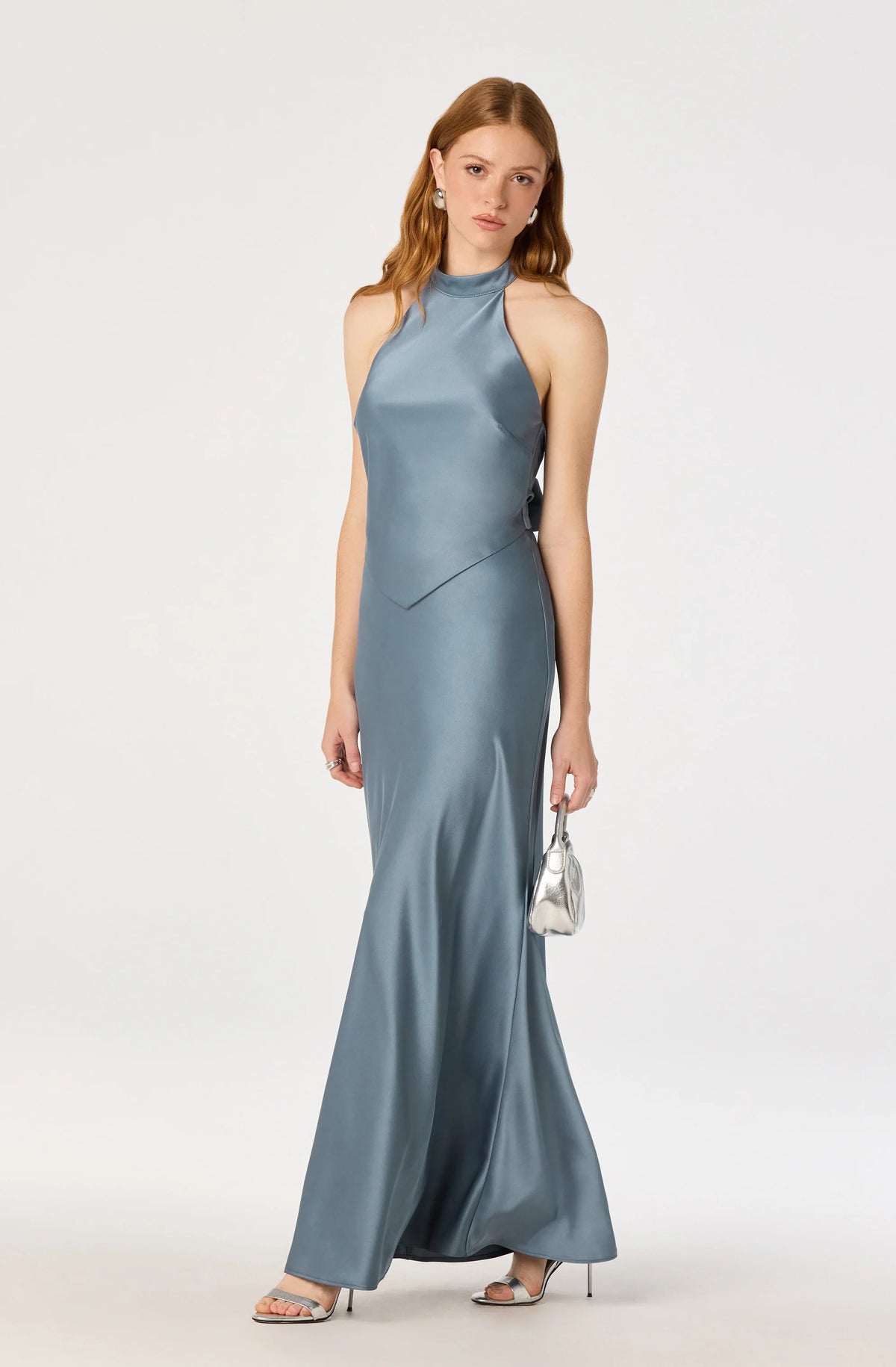 A model showcases a sleek satin halter maxi dress in a soft blue hue, featuring a high neckline and an elegant silhouette.