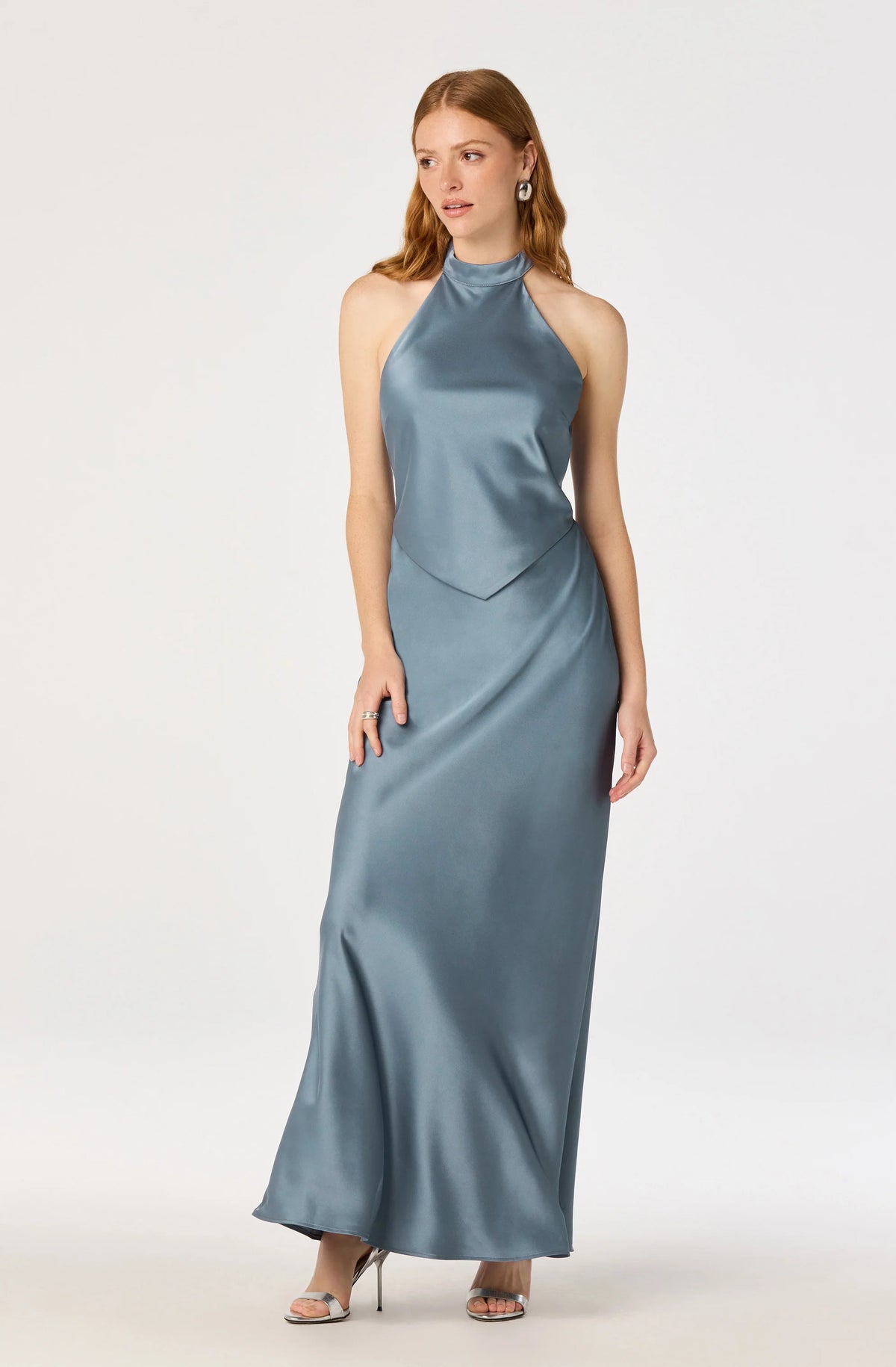 A model showcases a sleek satin halter maxi dress in a soft blue hue, featuring a high neckline and a flattering silhouette.