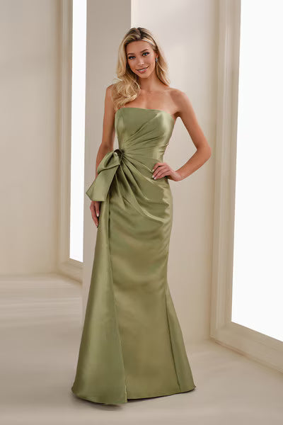 A model poses in a sleek, strapless apple green gown featuring a side bow detail. This elegant dress is perfect for formal occasions such as gala events, black-tie weddings, or as a stunning option for the mother of the bride,.